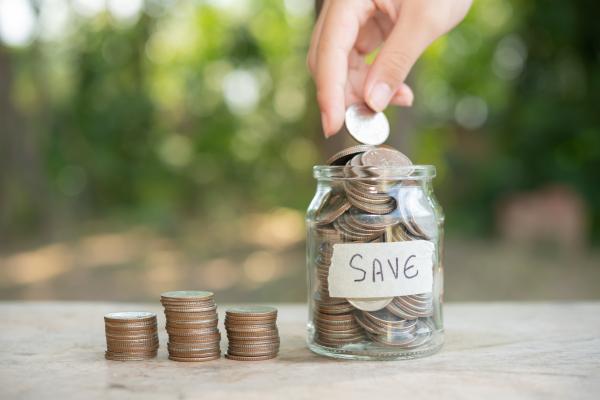 a woman putting coins in a saving jar
